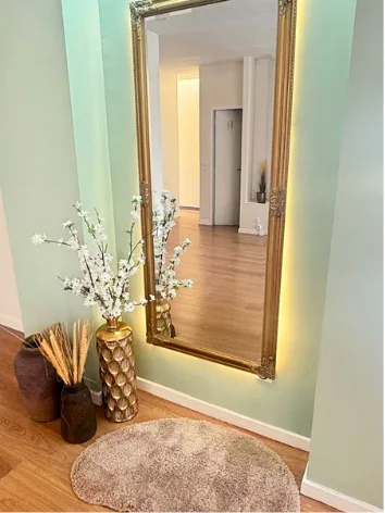 Entrada do espaço, com espelho dourado e flores